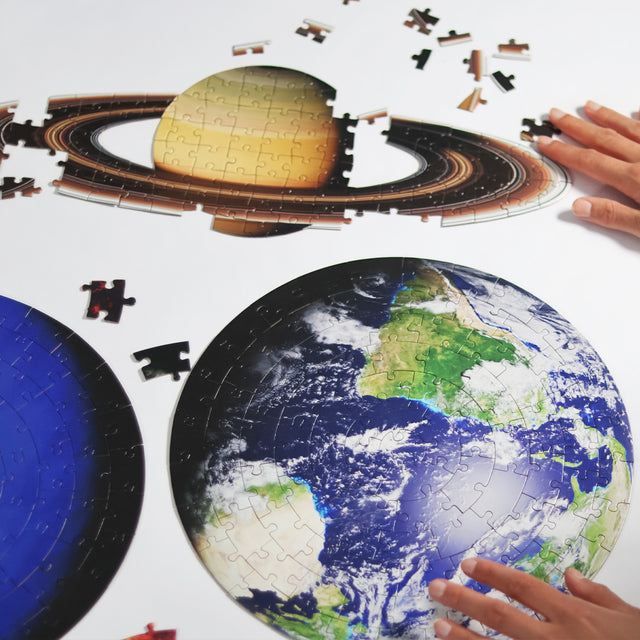 Pikkii planets jigsaw puzzle - hands piecing together Earth and Saturn