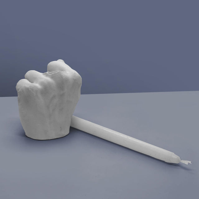 Pikkii Middle Finger Candle Holder with candle laying next to candle holder on Purple background