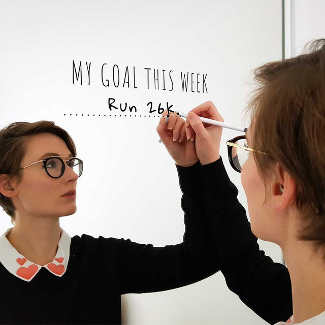 Woman writing her fitness goals on a mirror