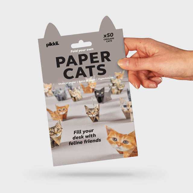 A pack of Paper Cats origami kits, featuring 50 fold-your-own cats and kittens of various colors and sizes, displayed with a hand holding the packaging.