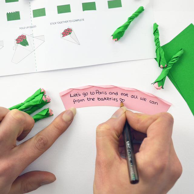 Writing a personalised not on a pink rose and rolling up into a little flower