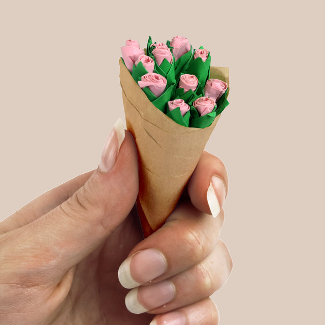 Hand holding a mini bouquet of pink paper craft roses