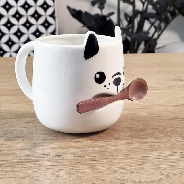 White Ceramic Dog Mug Holding A  Wooden Tea spoon in His Mouth on a Coffee Table