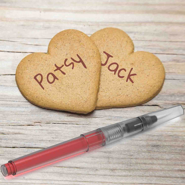 Two Heart shape cookies and food colouring pen on wooden surface