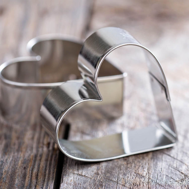 Artistic close up shot of two heart shaped cookie cutters on wooden surface