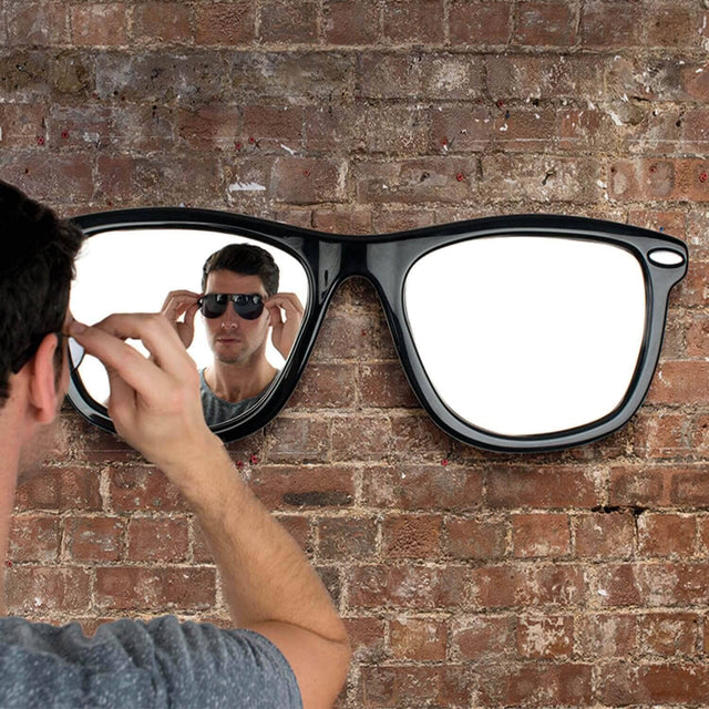 Man looking in the looking good sunglasses mirror hanging on brick wall