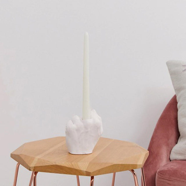 Pikkii Middle Finger Candle Holder with candle on side table next to a sofa chair