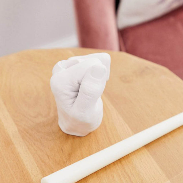 Pikkii Candle Holder with candle beside the cadle holder on a wooden table next to an armchair