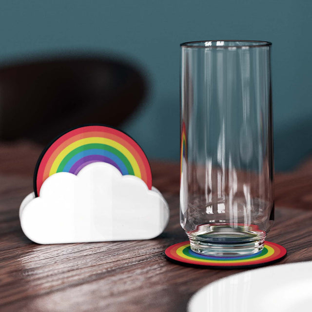 Nesting wooden rainbow coasters in a white ceramic cloud holder with an empty glass on a coaster