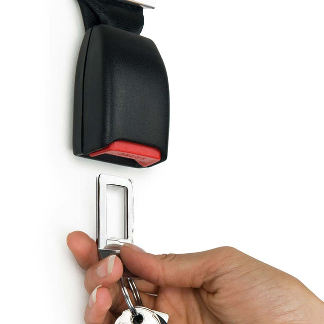 Hand holding keyring and keys plugging into Pikki Seatbelt Buckle Key Holder on white background
