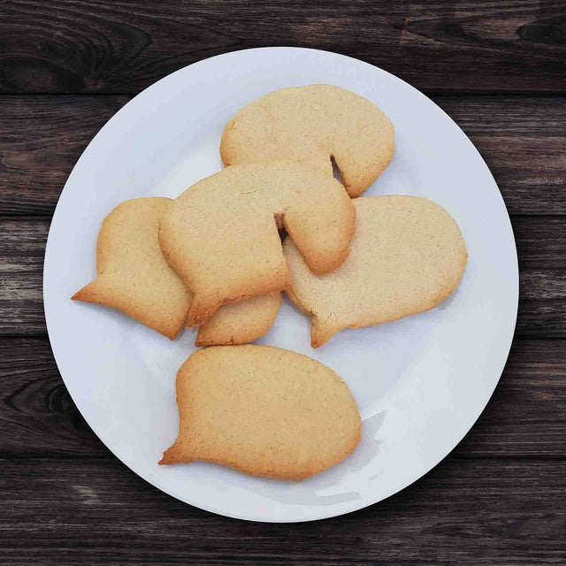 Plate of Speech Bubble Biscuits on white round plate on wooden table by Pikkii